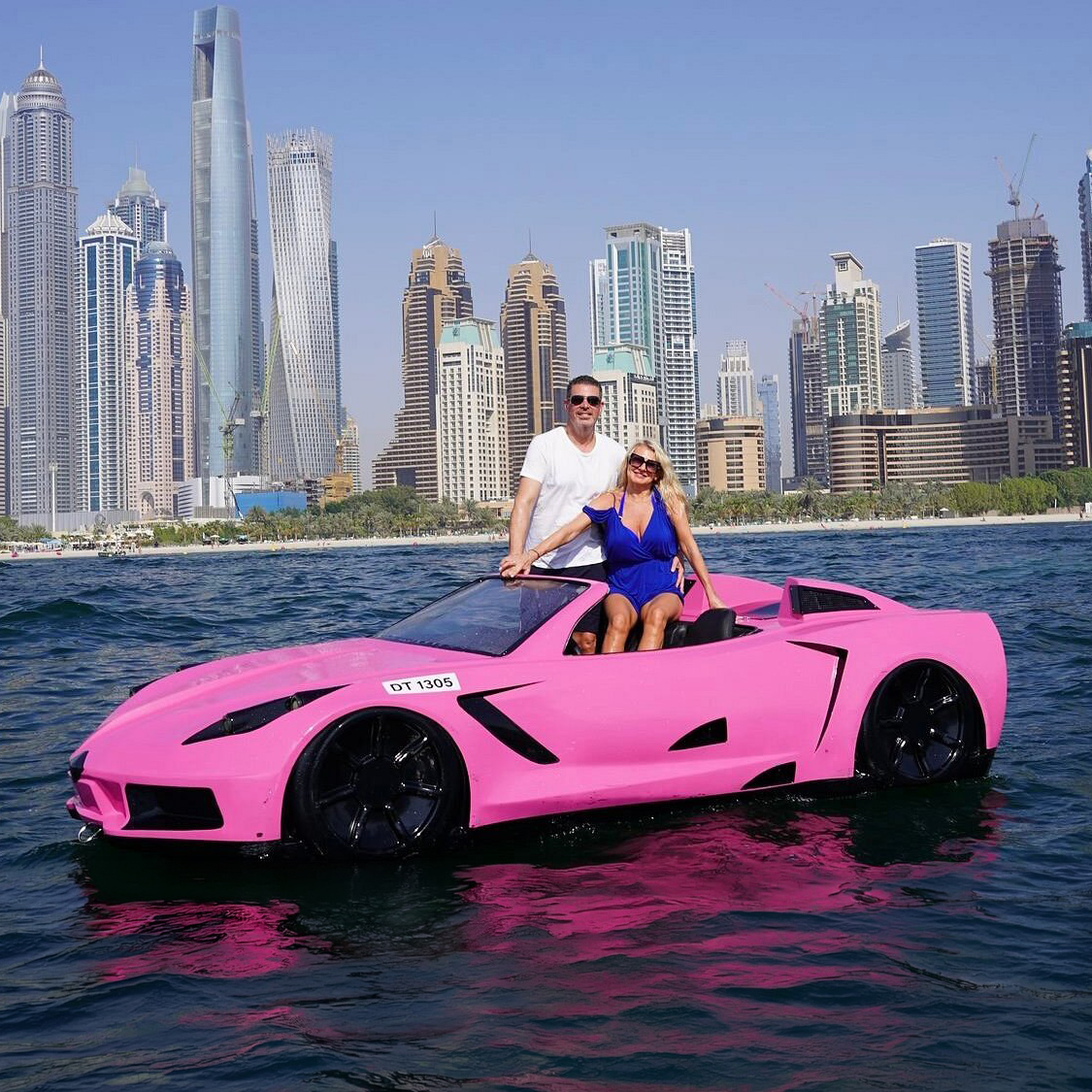 Couple enjoying a pink jet car ride on the sea with Dubai Marina skyline in the background