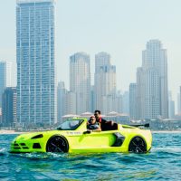 Two men riding neon green jet car near Dubai Marina skyline